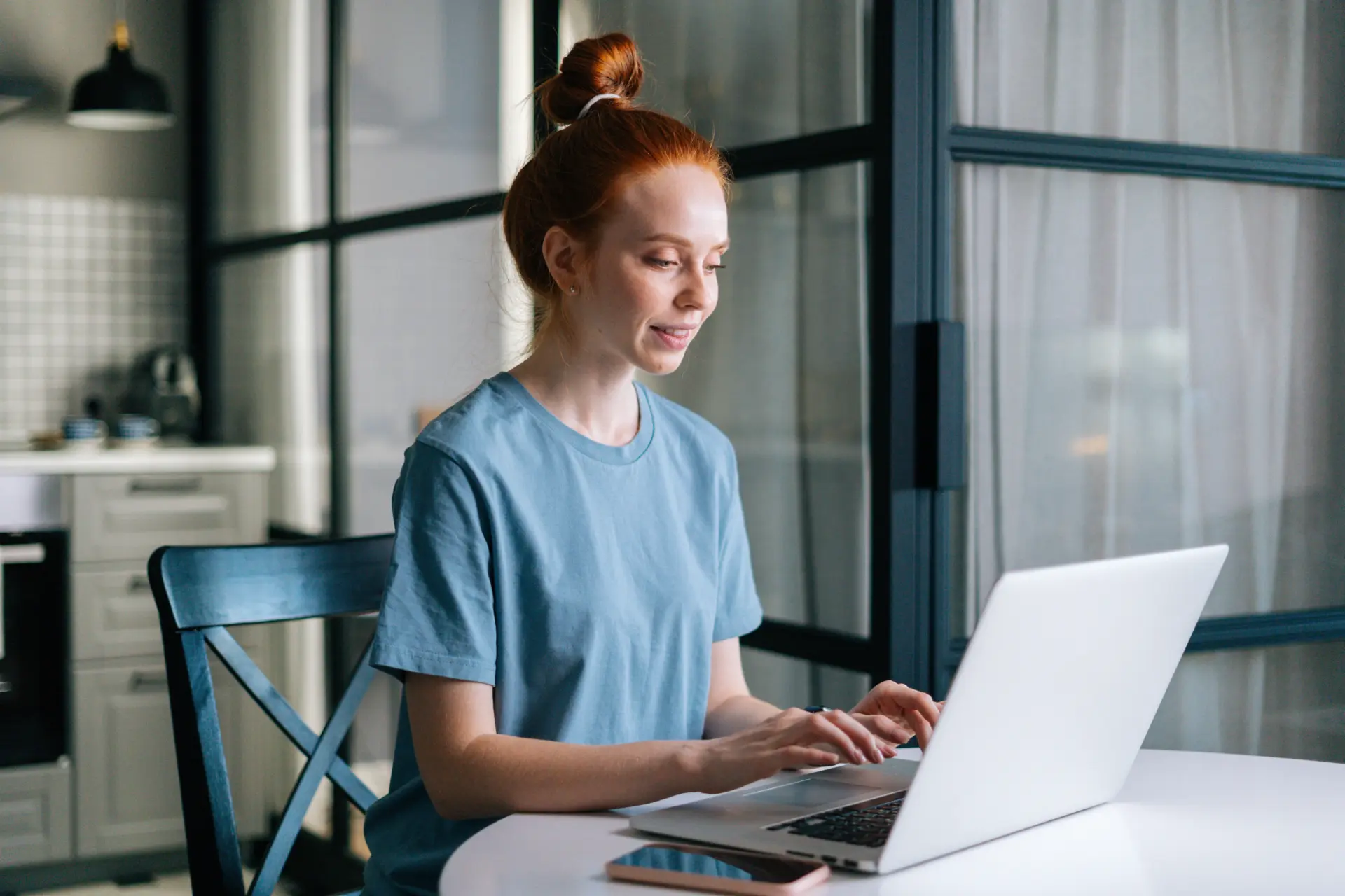 Seitenansicht Einer Laechelnden Jungen Frau Mit Rotschopf Die Am Tisch Am Laptop Arbeitet Und Am Laptop Sitzt